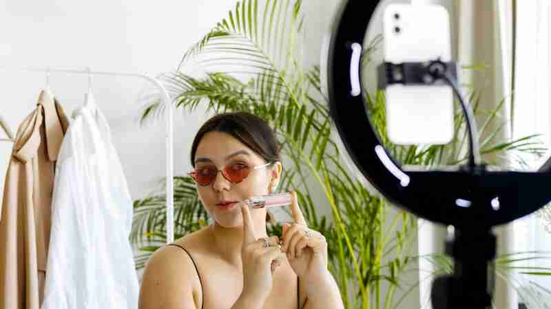 Fashion vlogger showcasing a cosmetic product with a smartphone and ring light setup., tags: vertrauen lokalen durch - pexel